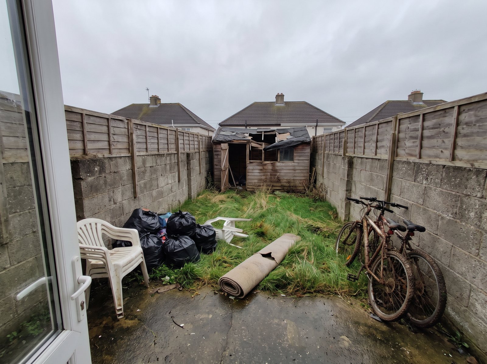 Back garden with a collapsed shed and bags, before
