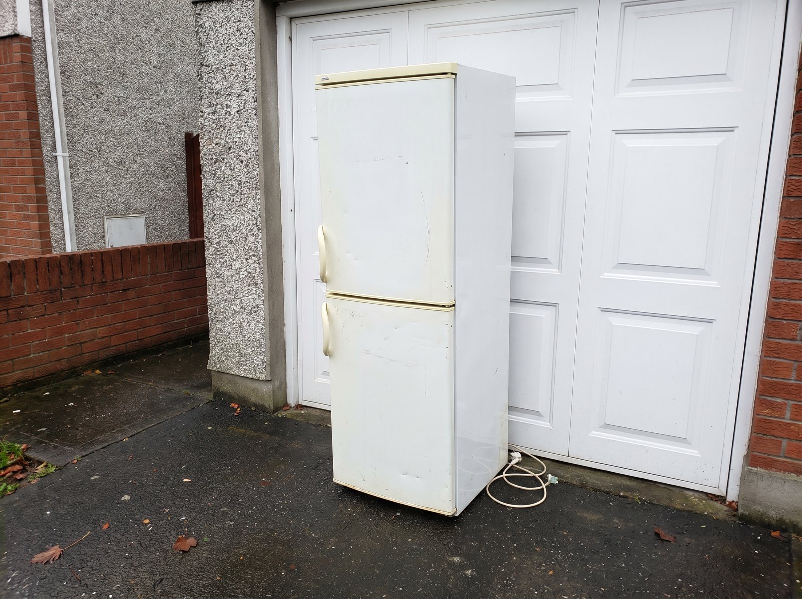 Old fridge-freezer outside a garage door, ready to be collected