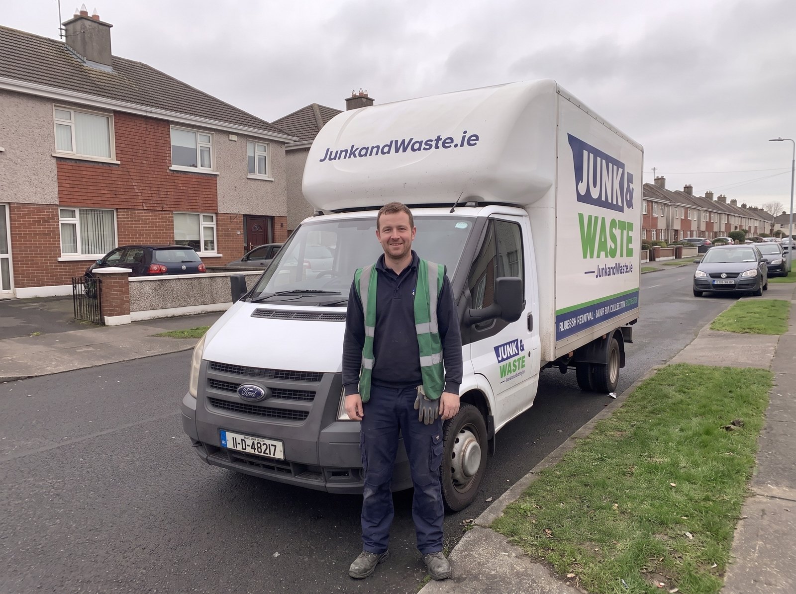 Junk & Waste crew member standing in front of the van on a Dublin estate road